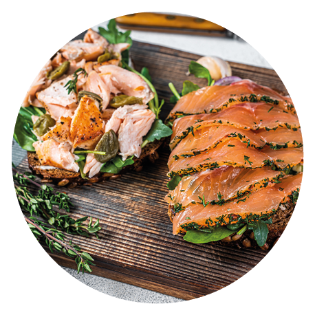 Sandwich toast with hot and cold smoked salmon, arugula and cream cheese on a wooden board. White background. Top view.