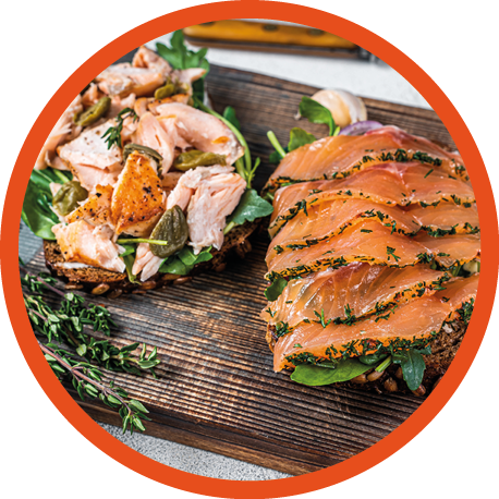 Sandwich toast with hot and cold smoked salmon, arugula and cream cheese on a wooden board. White background. Top view.